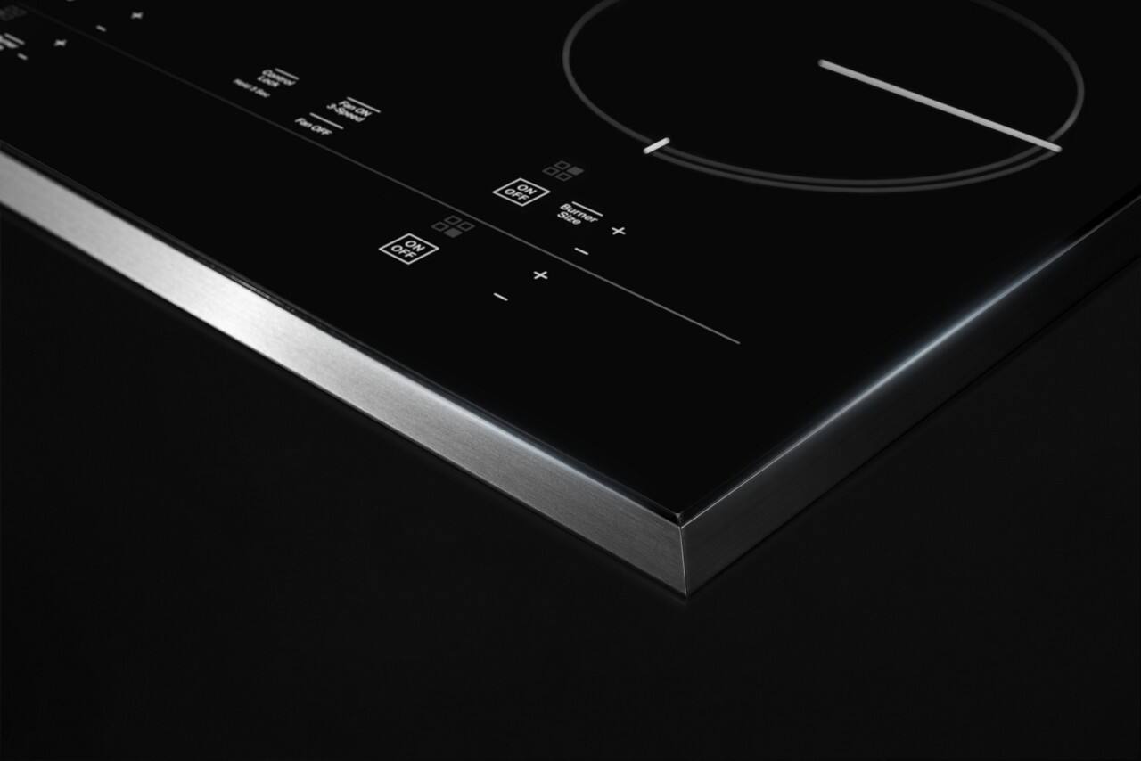 The image features an electric cooktop with a large knob on the left side and a smaller knob on the right side. The knobs are used to control the heat settings for the burners. The cooktop is black and silver in color, and the knobs are clearly visible in the image. The knobs are likely used to adjust the temperature of the burners, allowing for precise cooking control.