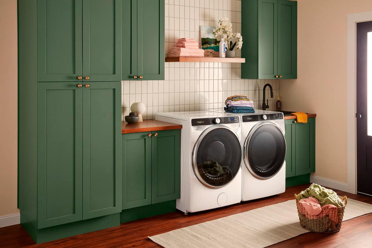 The text "SOWAH nir vagn" is not in English and does not make sense in the context of the image. The image shows a kitchen with a washer and dryer, a sink, and a counter. The washer and dryer are white, and the kitchen has green cabinets. The image does not provide any information about the text "SOWAH nir vagn."
