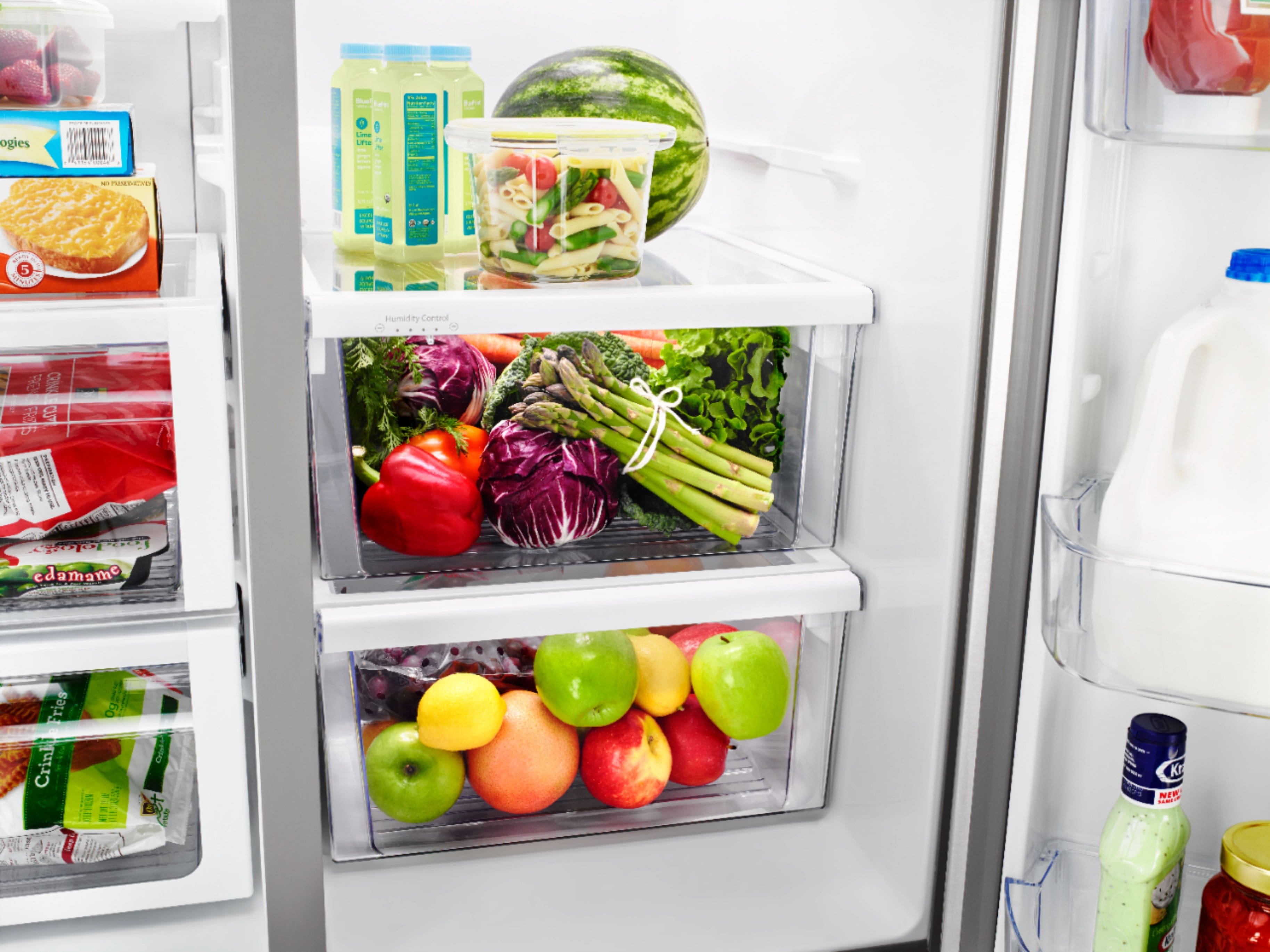 The image features a refrigerator filled with various food items, including a bowl of fruit, a bottle of water, and multiple bottles of beer. The refrigerator is stocked with a diverse assortment of food and drinks, making it a well-stocked and organized space. The presence of a variety of items in the refrigerator suggests that the owner has a diverse range of preferences and needs when it comes to their food and beverage choices.