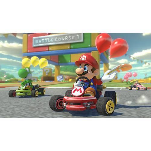The image shows a video game scene with a character driving a red kart, possibly Mario, on a race track. The character is holding a steering wheel and is surrounded by several balloons. There are also other karts visible in the scene, indicating a multiplayer or competitive game. The image captures the excitement and fun of the racing game, with the character navigating the track while enjoying the festive atmosphere created by the balloons.