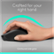 The image shows a person's hand holding a black computer mouse. The mouse is designed to fit comfortably in the user's right hand, providing a contoured side grip for better control and ease of use. The hand is positioned over the mouse, demonstrating how it can be used effectively.