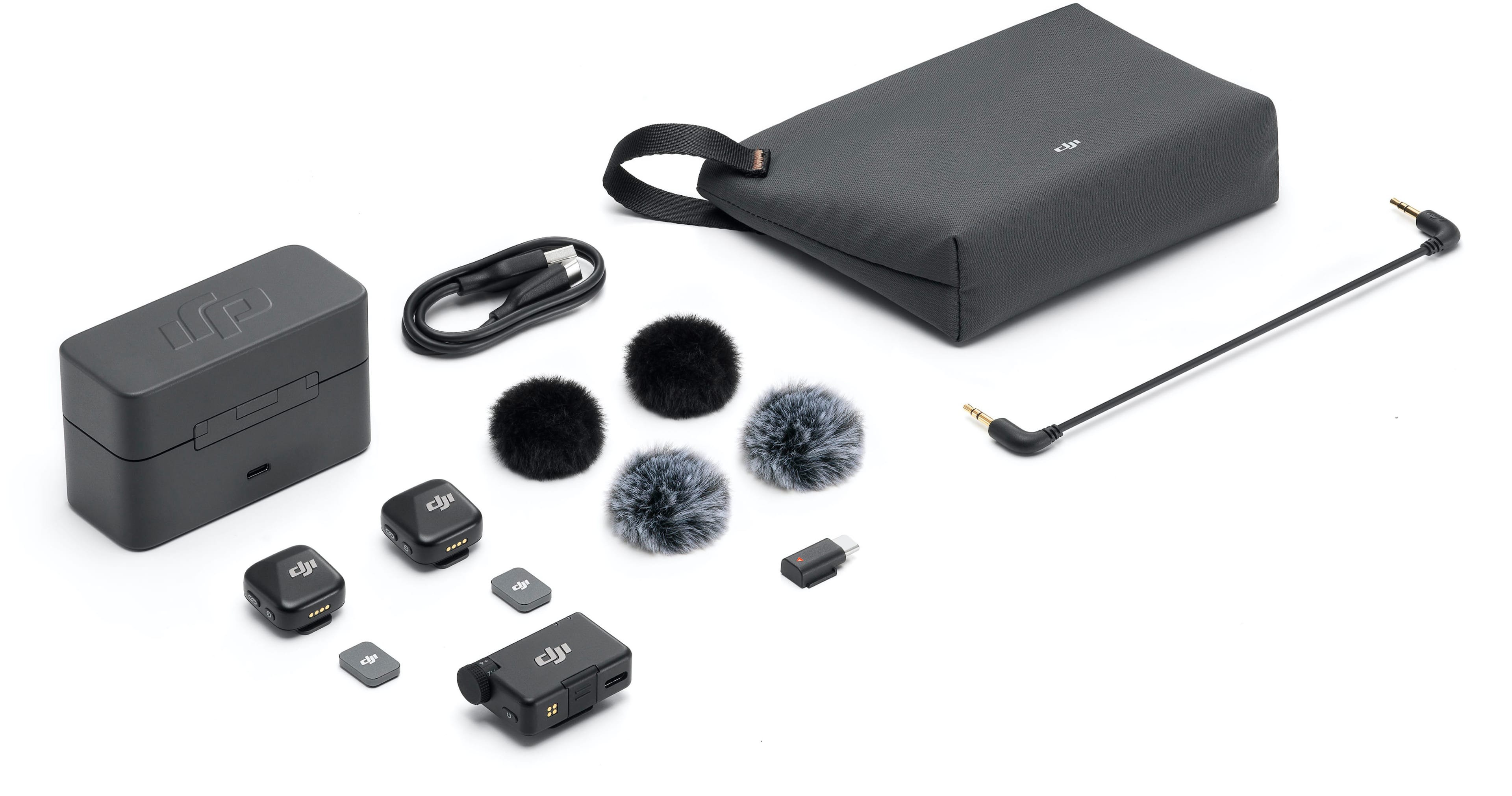 The image features a black case with various electronic equipment and accessories. The case contains a laptop, a mouse, a cell phone, and a pair of headphones. Additionally, there are two cords and a pair of earphones. The scene is set against a white background, which highlights the black case and its contents.