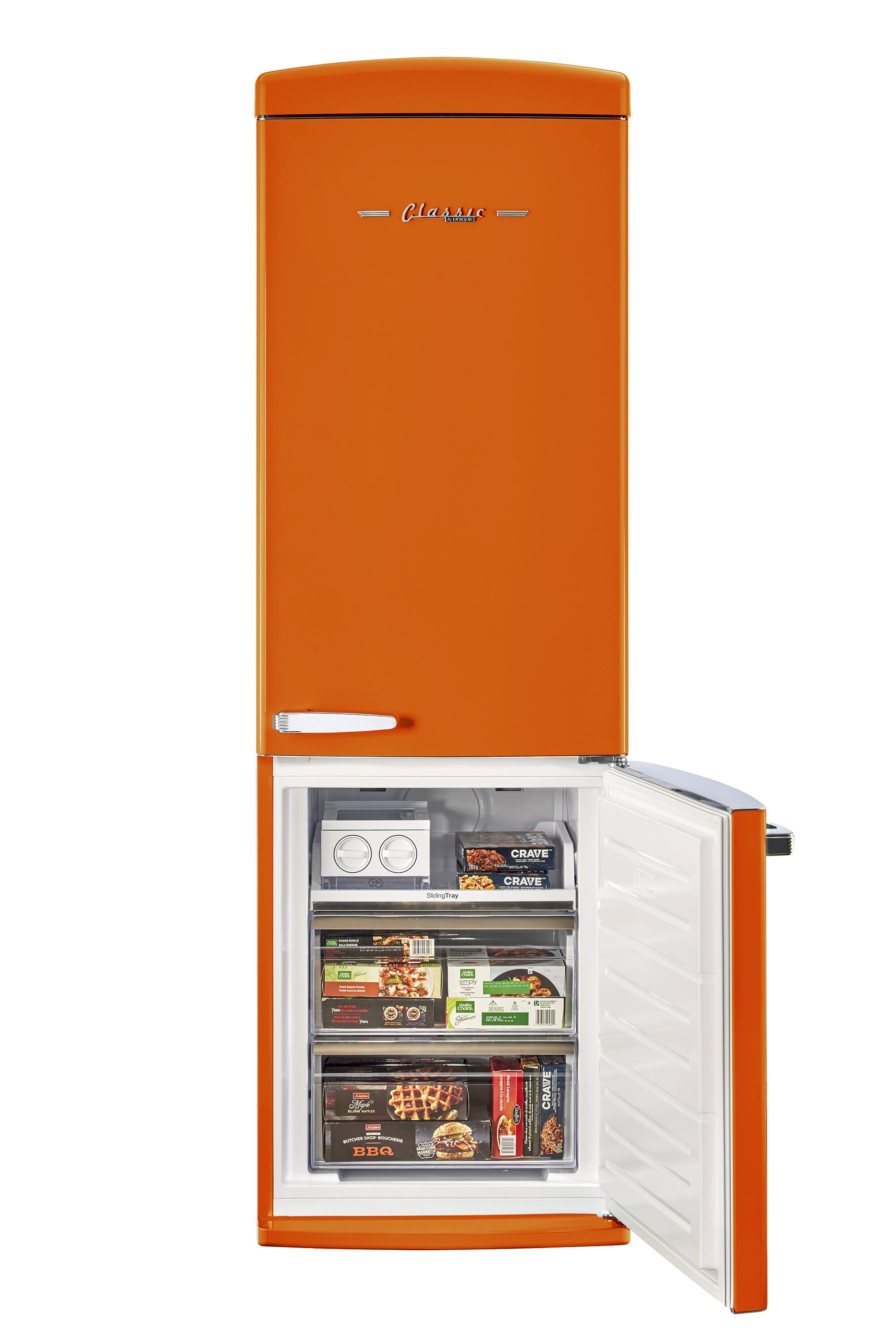 The image features a bright orange refrigerator with a white interior. The refrigerator is filled with various food items, including multiple bottles, a bowl, and a sandwich. The refrigerator is also stocked with a variety of snacks, making it a well-stocked and colorful appliance.