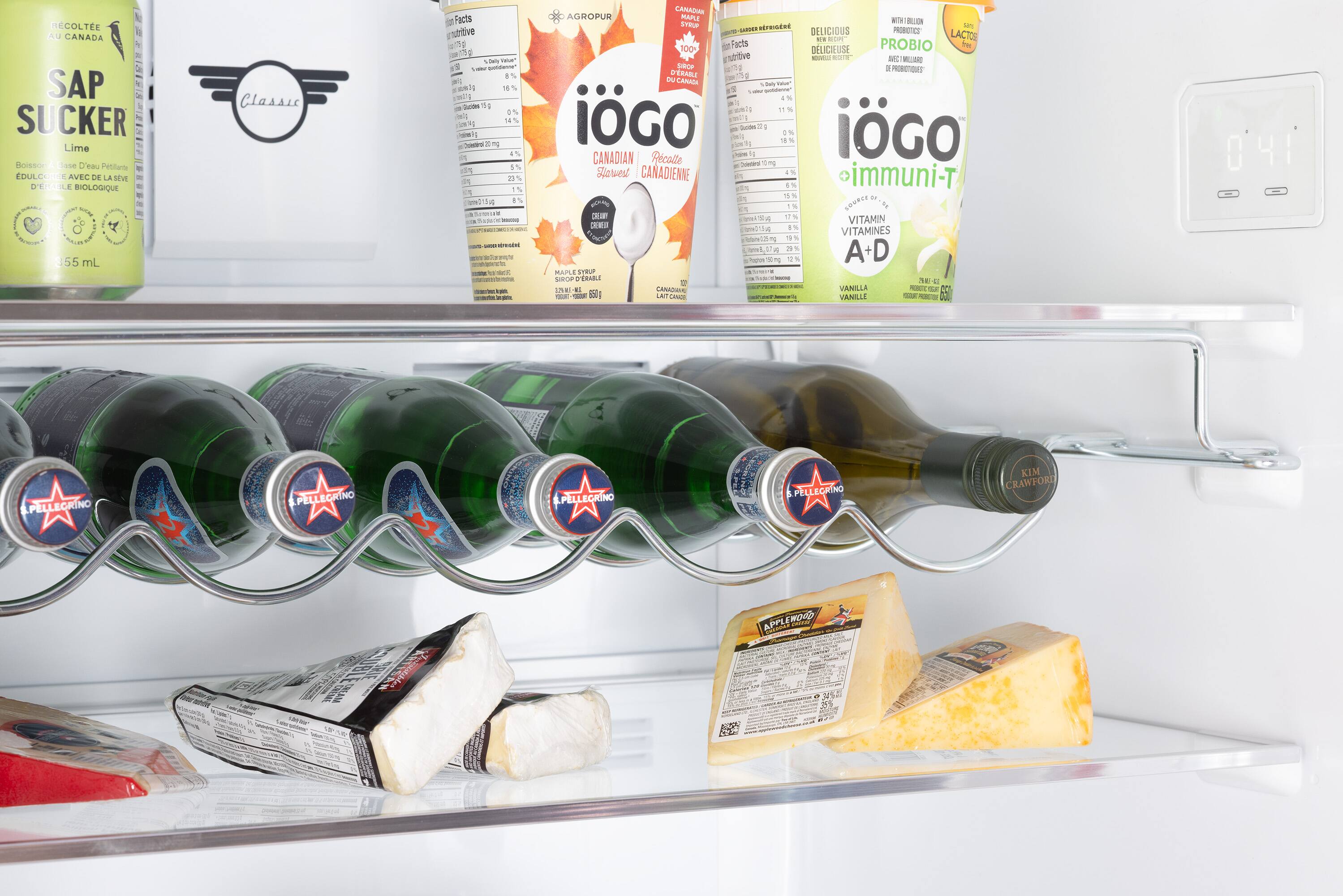 The refrigerator contains a variety of food items and drinks, including several bottles of wine, a carton of milk, and a carton of eggs. There are also some cheese and yogurt in the refrigerator. The refrigerator is well-stocked, providing a variety of options for meals and snacks.