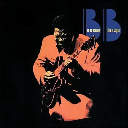The image features a man playing a guitar, with the letters "BB" and "King" above him. The man is wearing an orange jacket and appears to be performing on stage. The image is likely promoting a live performance by B.B. King in Japan.