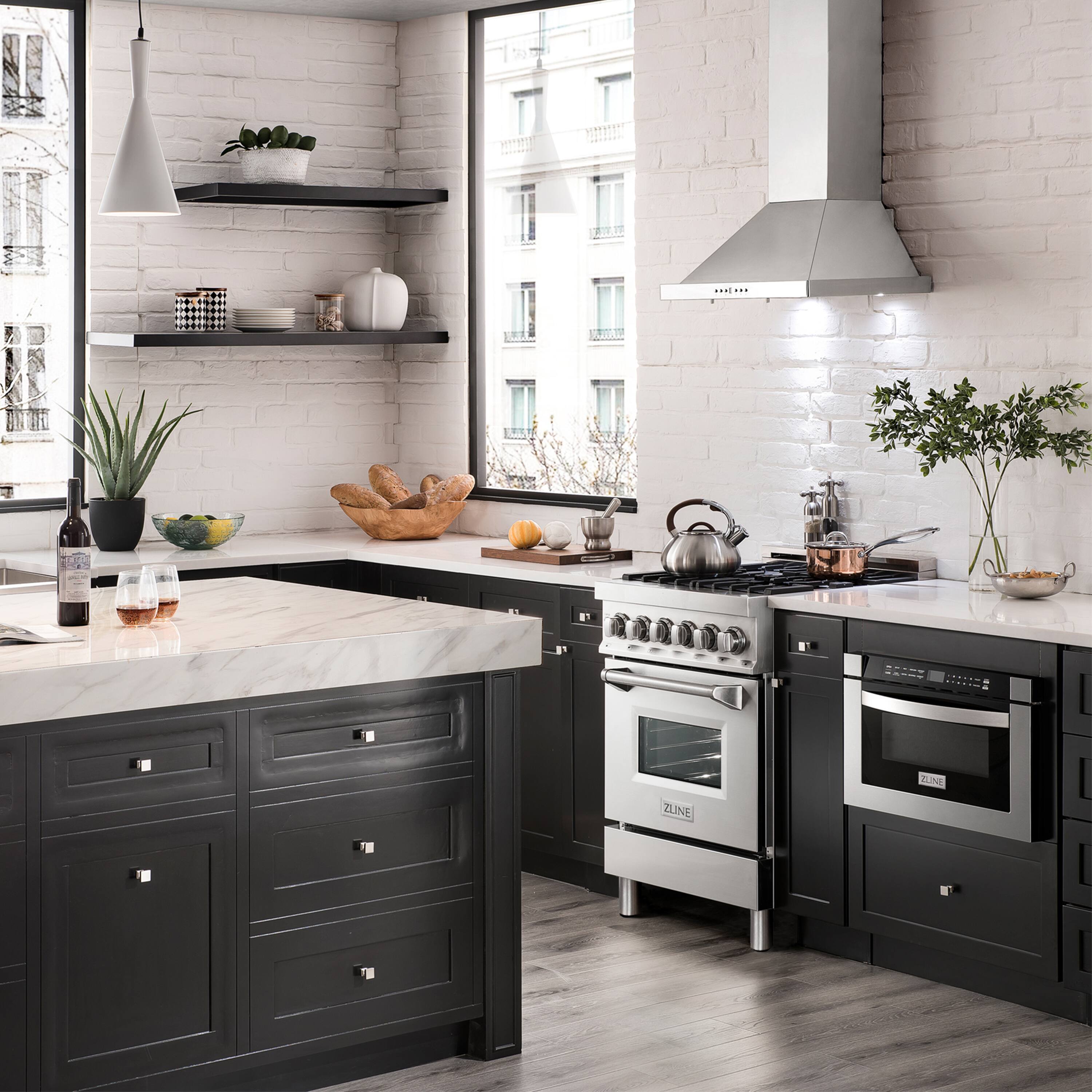 The image shows a modern kitchen with black appliances and white walls. The kitchen features a stove, oven, sink, and a large window. There are also several potted plants and a vase, adding a touch of greenery to the space. Additionally, there are multiple bowls and cups placed around the kitchen, as well as a bottle and a wine glass. The overall atmosphere of the kitchen is clean and contemporary.