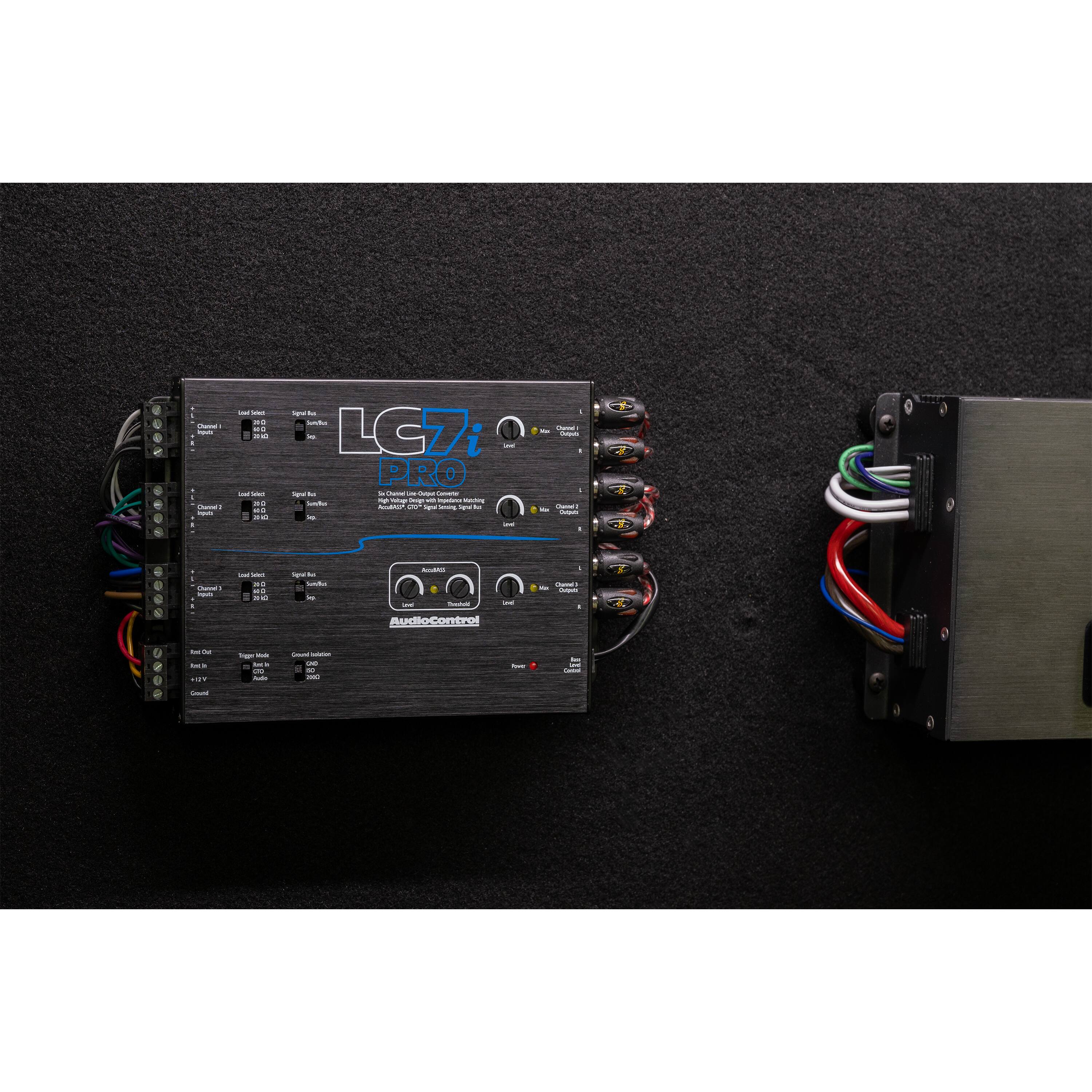 The LG7 PRO is a device that has multiple connections, including a power supply and a speaker. It is designed to be used with a computer and can be used for various purposes, such as connecting to a computer monitor, keyboard, or other peripherals. The device has a sleek black design and is placed on a black surface, possibly a table.