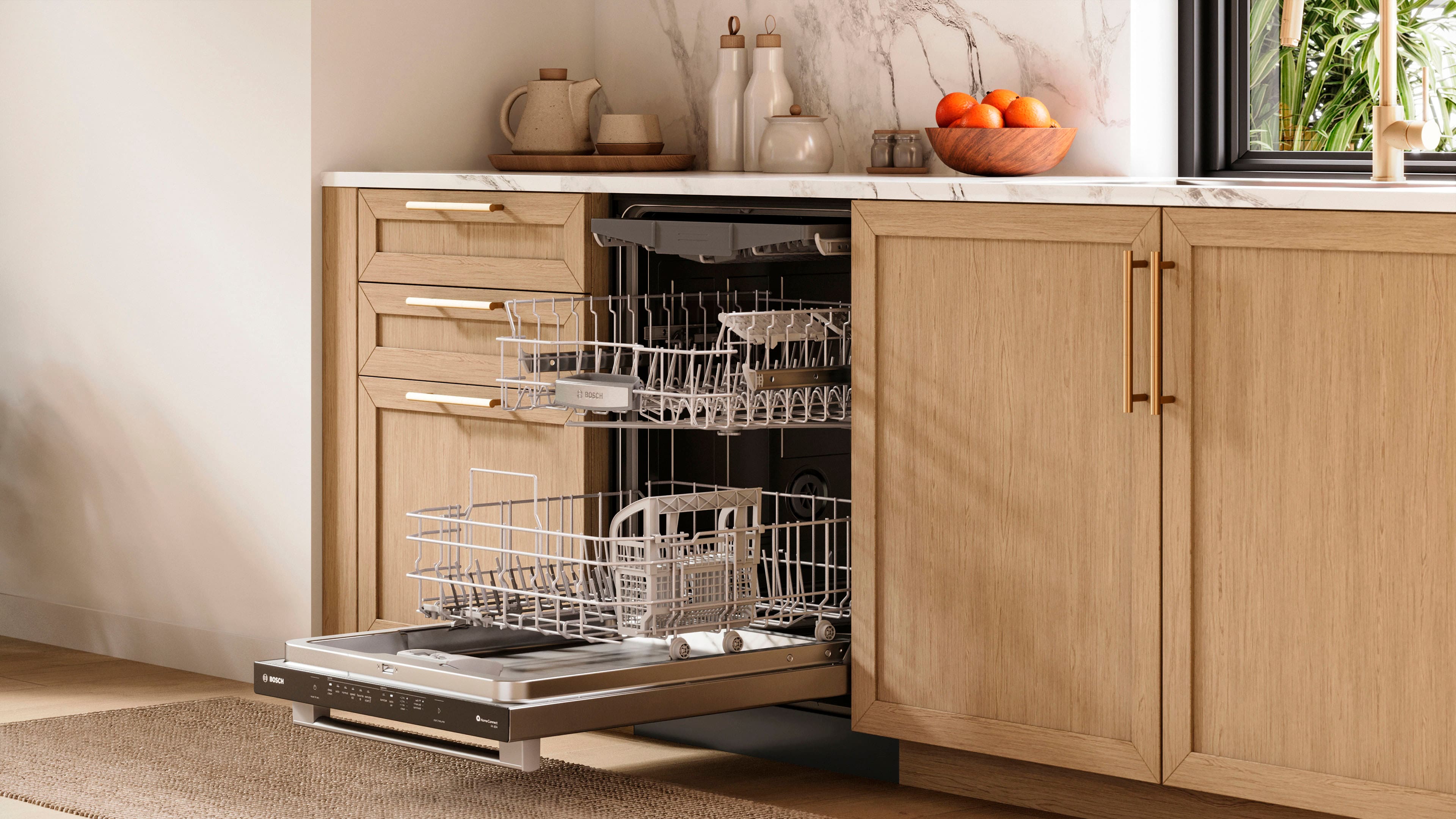 The image shows a kitchen with a dishwasher and a dish rack. The dishwasher is located under the counter, and the dish rack is placed on the counter. There are several dishes, including cups and bowls, placed on the counter and in the dishwasher. Additionally, there are oranges and a potted plant visible in the scene.