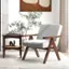 The image shows a living room with a chair, table, and a potted plant. The chair is positioned in front of the table, which has a book on it. The potted plant is placed next to the chair, adding a touch of greenery to the room. The living room is decorated with a painting on the wall, and the overall atmosphere appears to be cozy and inviting.