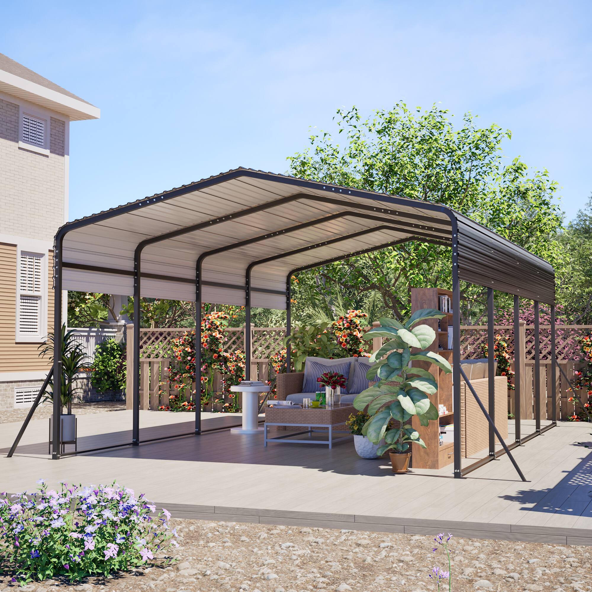 The image shows a modern outdoor patio setup with a metal pergola providing shade. The patio features a wooden deck, a wicker sofa with cushions, a small round table, and various potted plants. The background includes a house with beige siding and a garden with colorful flowers and greenery.