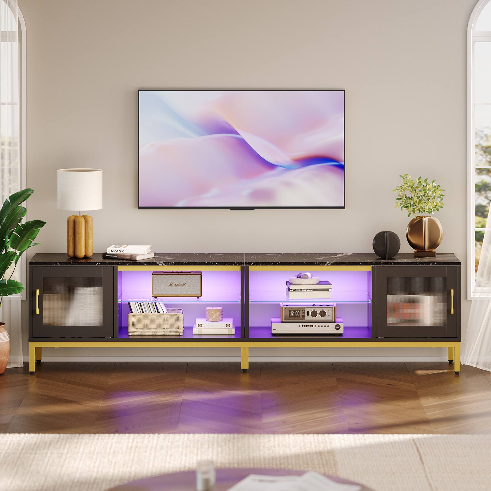 I am a modern design with a large flat screen TV sitting on top of a wooden entertainment center. The entertainment center has a purple light underneath it, and it is adorned with various books and decorative items. The TV is placed on a wall, and there is a potted plant nearby, adding a touch of greenery to the room.