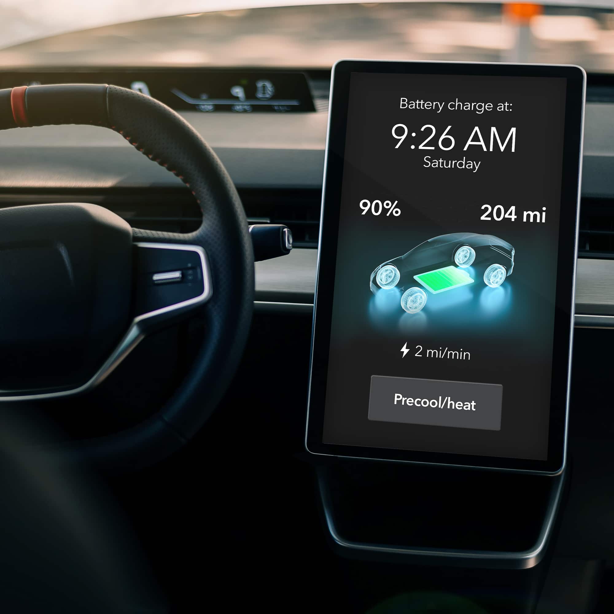 The image shows a car's dashboard with a display screen showing the battery charge level, the time, and the day. The text reads: "Battery charge at: 9:26 AM Saturday 90% 204 mi 2 mi/min Precool/heat."