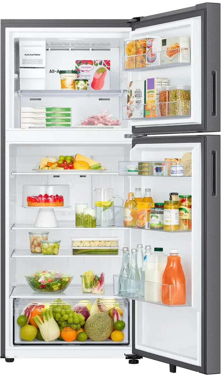 The image shows a refrigerator with its door open, revealing a variety of food items inside. There are several bottles, including milk, juice, and water, as well as a bowl of fruit and a tray of vegetables. The refrigerator is well-stocked with a diverse selection of food, making it a convenient and healthy option for meal preparation.
