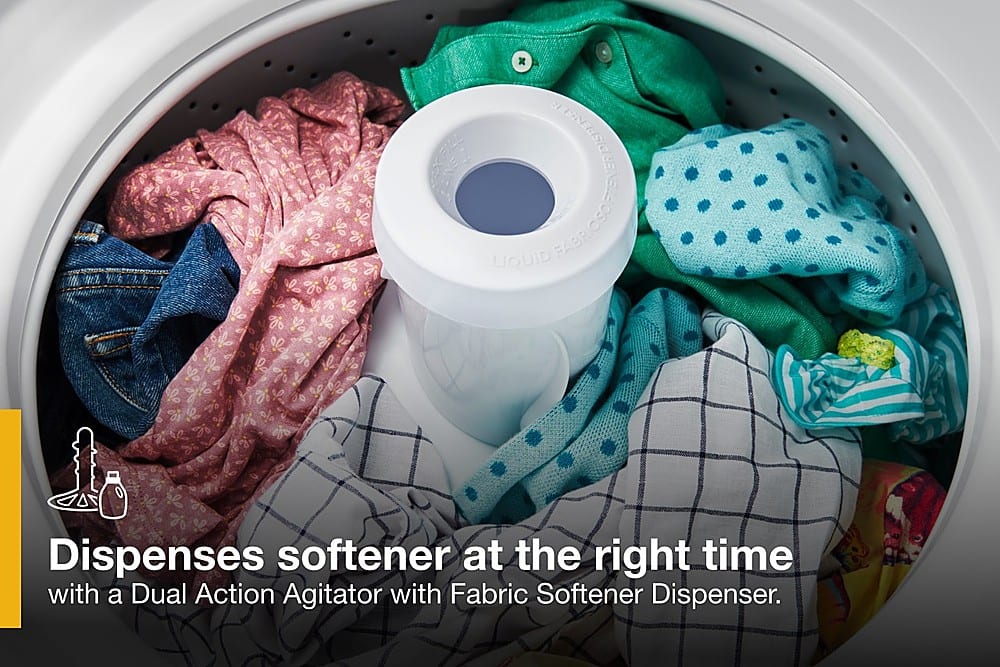 The image shows a washing machine filled with clothes, with a dispenser of softener sitting on top of the machine. The machine is designed to dispense softener at the right time, ensuring that the clothes are soft and comfortable to wear. The dual action agitator with a fabric softener dispenser helps to evenly distribute the softener throughout the wash cycle, providing optimal results.