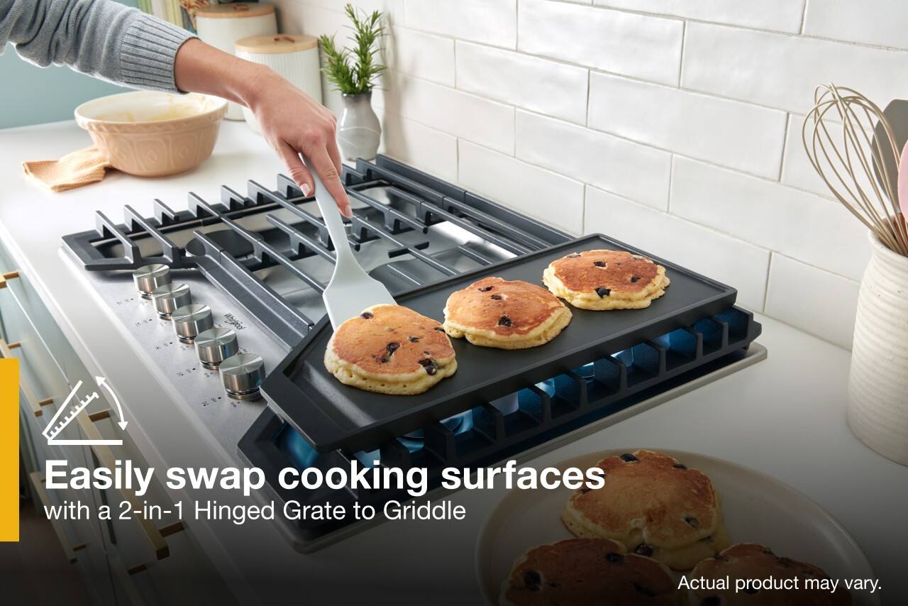 The image features a person using a spatula to flip pancakes on a griddle. The griddle is placed on top of a stove, and there are multiple pancakes being cooked. The person is using a spatula to easily swap cooking surfaces with a 2-in-1 Hinged Grate to Griddle. The actual product may vary, but the image showcases the convenience and efficiency of using a spatula for cooking tasks.