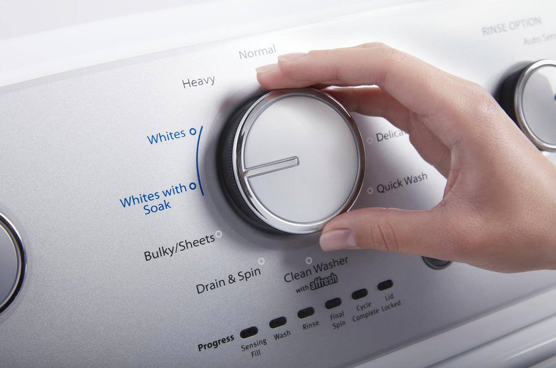 The image shows a person's hand pressing a button on a Whirlpool washing machine. The machine has four different soil level selections, which can be selected by the user to ensure the right setting for their laundry. The hand is pressing the "Heavy" soil level button, indicating that the user has chosen the appropriate setting for their laundry.