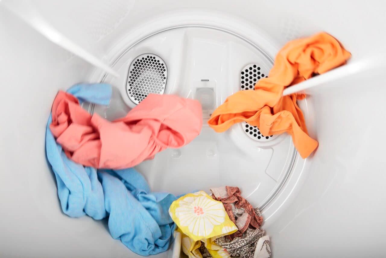 The image features a white Whirlpool washing machine with a wrinkle shield option. The machine has a hamper door and is designed to hold 7.0 cubic feet of laundry. The washing machine is placed in a room with a wooden floor.