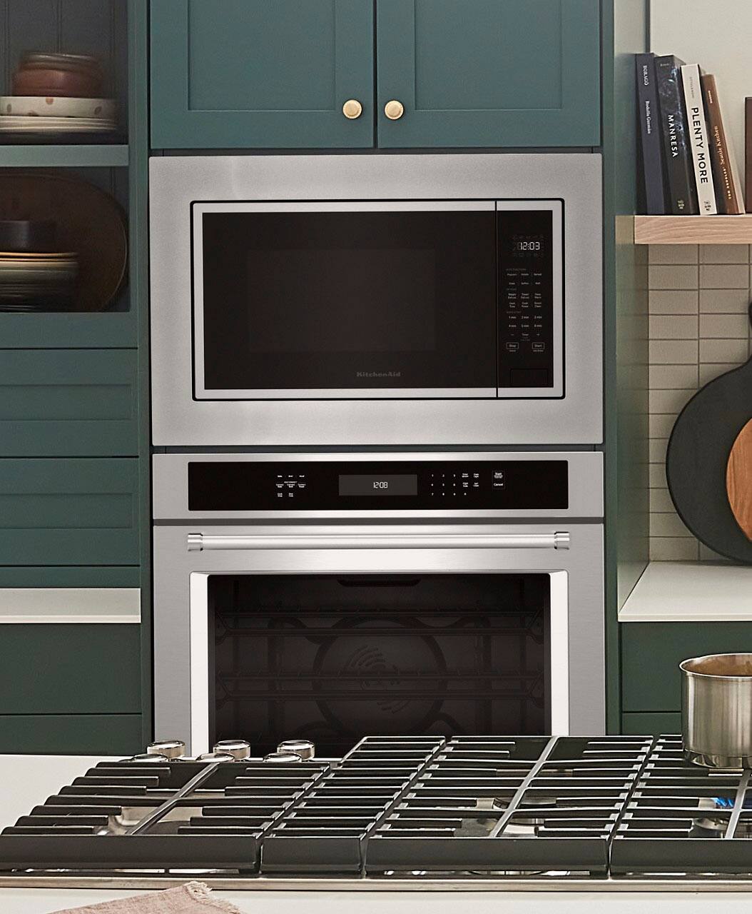 The text on the image reads "BOY nGns MANRESA PLENTY Knches I MORE 12:03 KitchenAid - 200 - -". This text seems to be a combination of different sentences and phrases, but it does not provide any context or information about the image of the stove and microwave.