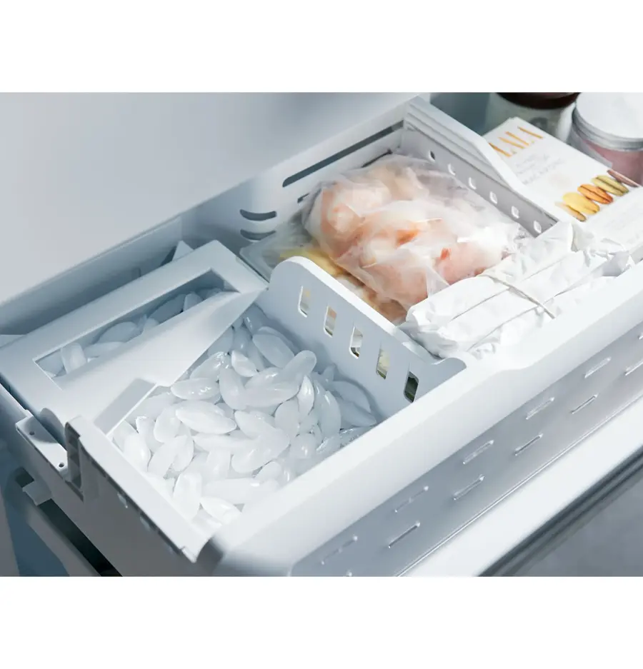 The image shows a refrigerator with its door open, revealing a drawer filled with ice and a tray of raw chicken. The drawer is filled with ice, which is likely used to keep the chicken fresh and cold. The chicken is placed in a plastic bag, ensuring it stays clean and protected. The refrigerator is filled with various items, including a bowl and a book, which can be seen on the top shelf.
