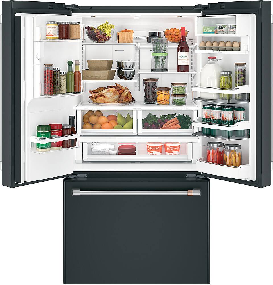 The image shows a refrigerator filled with a variety of food items, including fruits, vegetables, and bottles. The refrigerator has a black door and is stocked with a wide assortment of items, such as broccoli, carrots, oranges, and apples. There are also several bottles placed throughout the refrigerator, with some located in the door compartments and others placed on the shelves. The refrigerator is well-organized, making it easy to find and access the desired items.