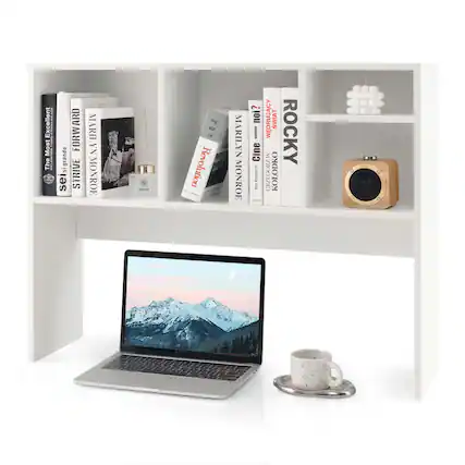 The image features a white desk with a laptop computer and a cup of coffee on it. The desk is also filled with numerous books, some of which are placed on a shelf above the laptop. The books are arranged in a neat and organized manner, creating a visually appealing and functional workspace. The presence of the coffee cup suggests that the person using the desk might be working or studying for an extended period, and the books indicate that they are likely engaged in research or learning.