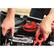 A person is working on a car, holding a red tool in one hand and a black tool in the other. The car is equipped with a battery and a charger, and the person is likely performing maintenance or repairs. The image shows the person's hands gripping the tools, with the red tool being held in the right hand and the black tool in the left hand. The focus of the image is on the person's hands and the tools they are using, highlighting the task at hand.