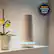 The image features a white device, possibly a security system, sitting on a shelf next to a vase with flowers. The device is prominently displayed in the scene, and the vase with flowers adds a touch of elegance to the setting. The image is categorized as Household_Detectors_and_Sensors, and it requires a SimpliSafe Security System.