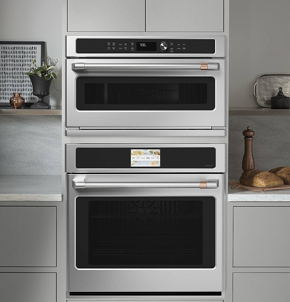 The image features a stainless steel oven with a stove top and a toaster oven on top of it. The oven is placed in a kitchen setting, with a counter nearby. There are also two potted plants in the scene, one on the left side and the other on the right side of the oven. Additionally, there is a vase on the left side of the oven, and a bowl can be seen on the right side.