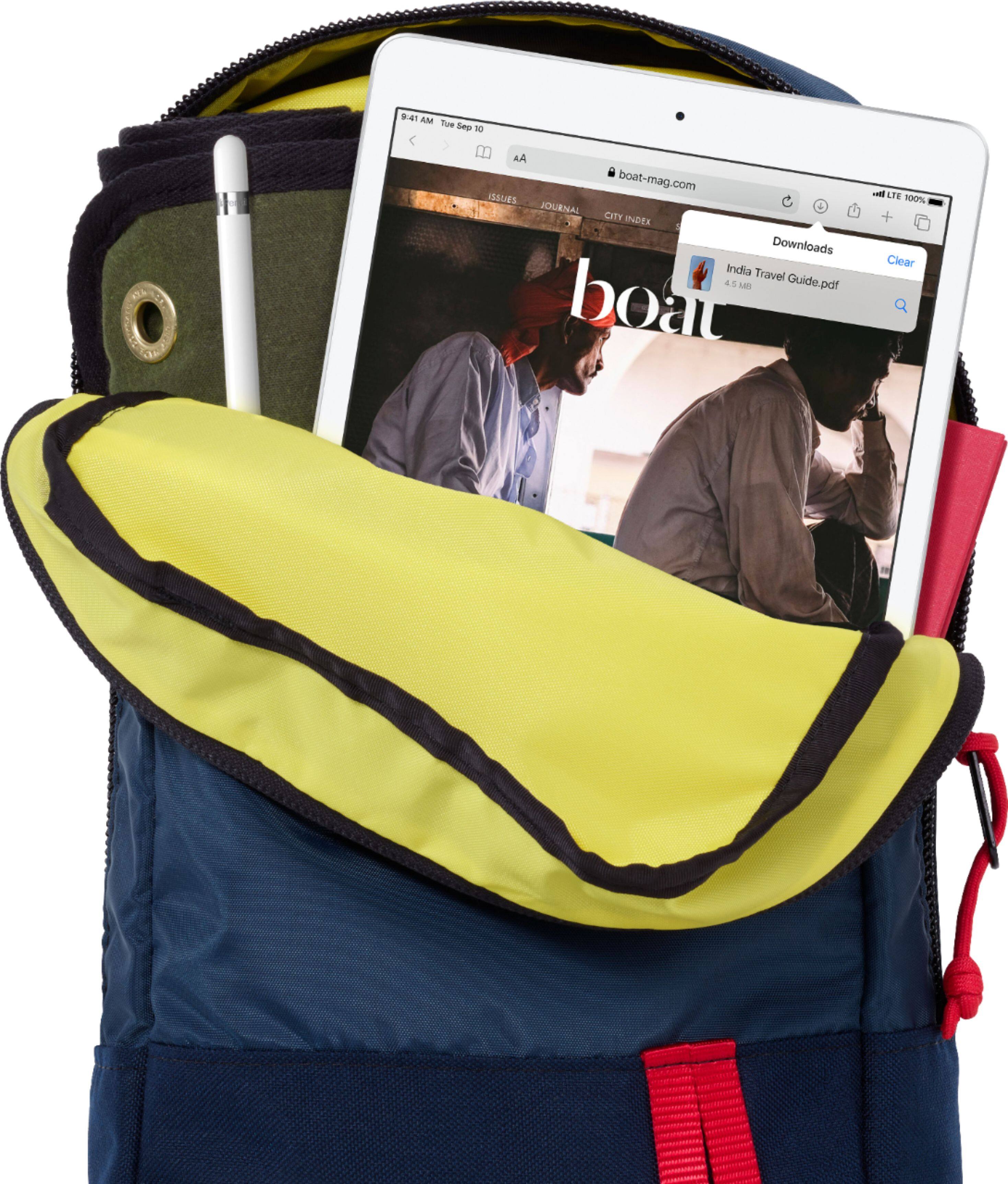 The image shows a blue and yellow backpack with a tablet computer and a pen inside. The tablet is displaying a website called "boat-mag.com," which is likely related to boating or water-based activities. The backpack is likely used for carrying essential items, such as the tablet and pen, while traveling or working.