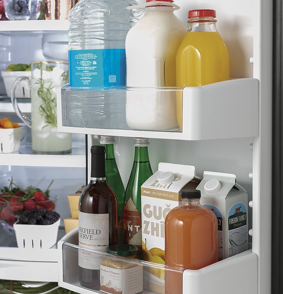 The image shows a refrigerator with several bottles of drinks and milk on the shelves. There are three bottles of milk, one on the top shelf, another on the middle shelf, and the third one on the bottom shelf. Additionally, there are three bottles of juice, with one on the top shelf, another on the middle shelf, and the third one on the bottom shelf. The refrigerator also contains a bowl of fruit, which is placed on the bottom shelf.