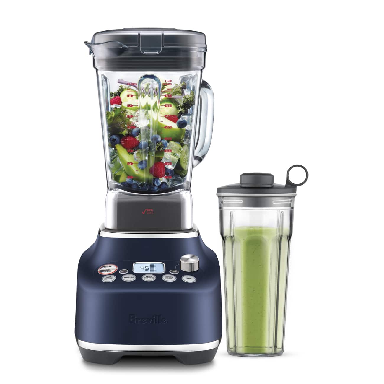The image features a blue Breville blender with a green container next to it. The blender is filled with a mixture of fruits and vegetables, including apples, oranges, and broccoli. The green container appears to be a measuring cup, possibly for measuring the ingredients used in the blender. The blender is placed on a countertop, ready for use.