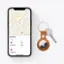 The image features a smartphone with a map application open, displaying the location of Alan's keys. The phone is placed next to a car key, which is attached to a keychain. The keychain is designed to resemble an Apple logo, adding a touch of personalization to the key. The scene suggests that the person using the phone has found their keys and is ready to continue with their plans.