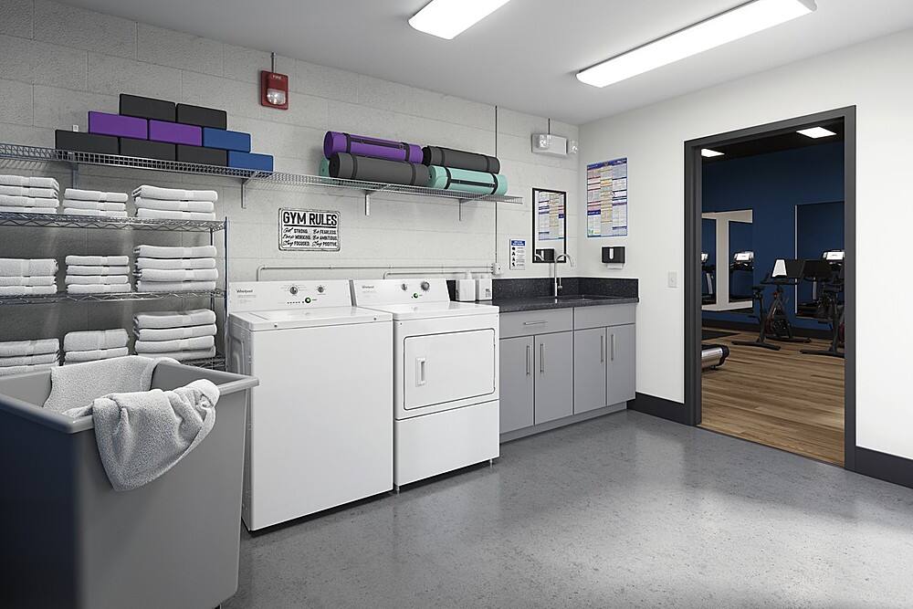 The image features a laundry room with a washer and dryer, a sink, and a shelf with towels. The room also has a gym area with a treadmill and a bench. The sign on the wall states "Gym Rules."