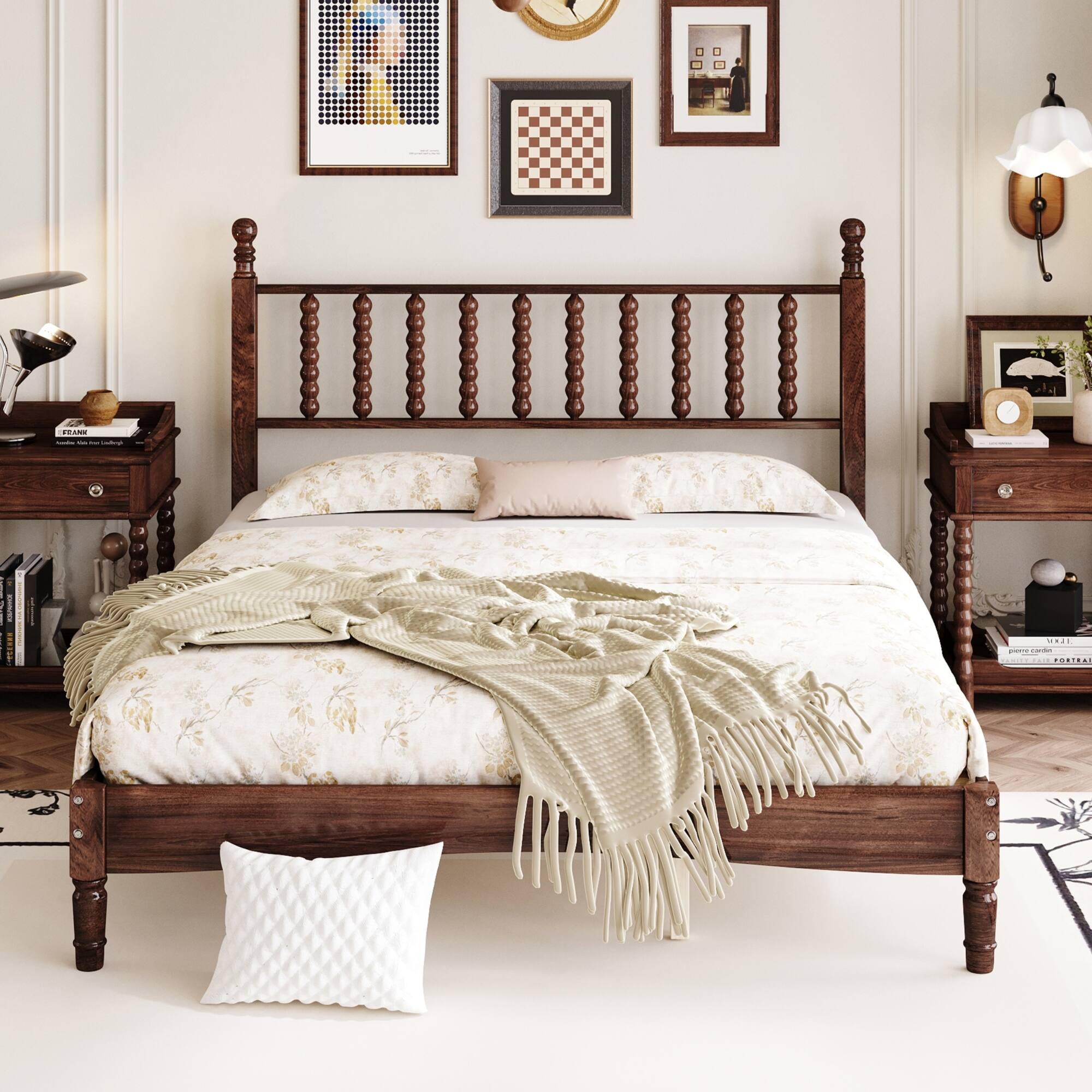 A classic wooden bed with a floral-patterned comforter and a beige throw blanket. The headboard features turned spindles, and the bed is flanked by matching wooden nightstands. Above the bed, there are framed artworks, including a pixelated portrait and a chessboard design. A white quilted pillow rests on the floor at the foot of the bed.