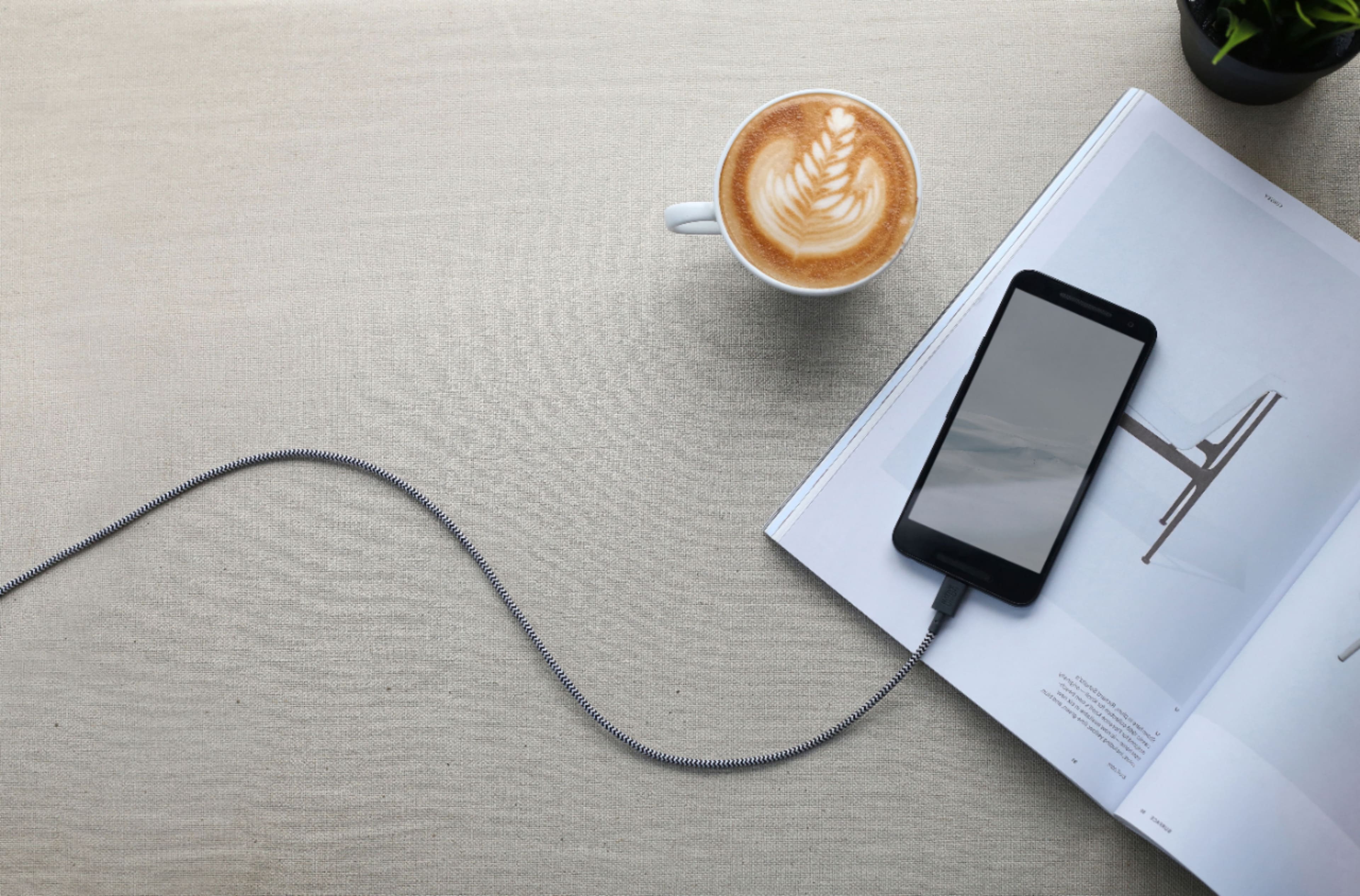 I cannot group or correct the text as it does not appear to be coherent or related to the image. The image shows a cell phone, a coffee cup, and a magazine on a table.