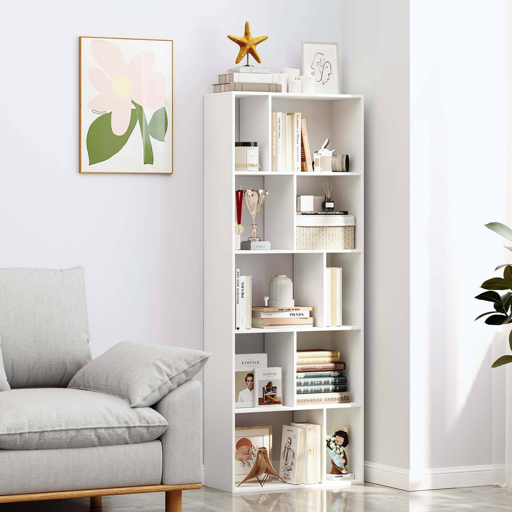 The image features a white bookshelf filled with various items, including books, a star, and a vase. The bookshelf is situated next to a couch, and there is a picture hanging on the wall above the shelf. The books on the shelf are arranged in different positions, and the overall scene creates a cozy and inviting atmosphere in the living room.