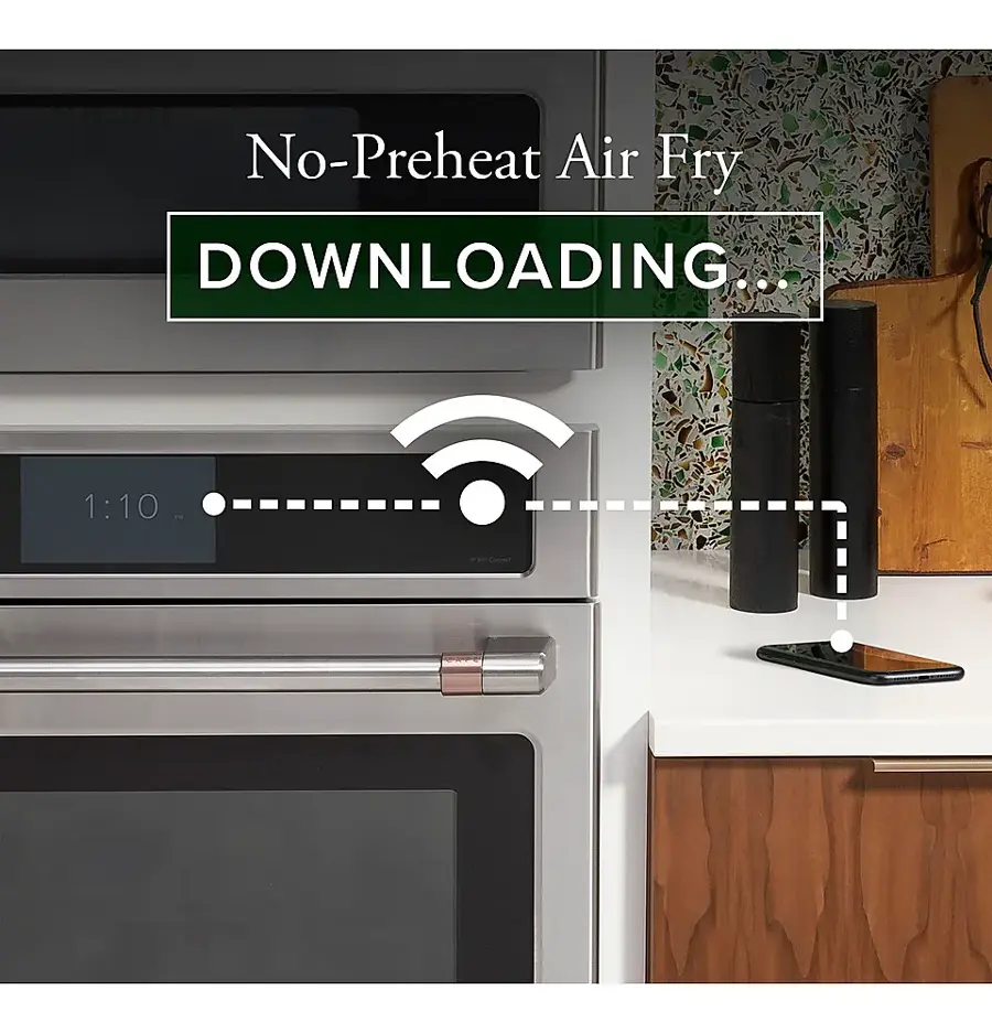The image features a kitchen with a microwave and an oven. The microwave has a no-preheat air fry feature, and it is currently downloading. The oven is located next to the microwave, and there is a cell phone placed on the countertop. The kitchen also has a sink and a spoon nearby.