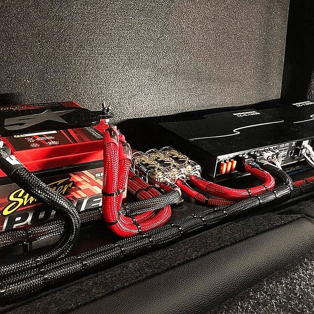 The image shows a black case with a red and black battery pack inside. The battery pack is connected to a black wire and a red wire, which are both plugged into the case. The case is likely used to store and transport the battery pack and its wires.