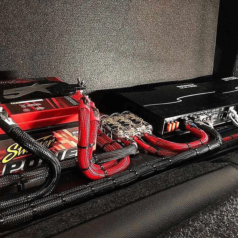 The image shows a black case with a red and black battery pack inside. The battery pack is connected to a black wire and a red wire, which are both plugged into the case. The case is likely used to store and transport the battery pack and its wires.