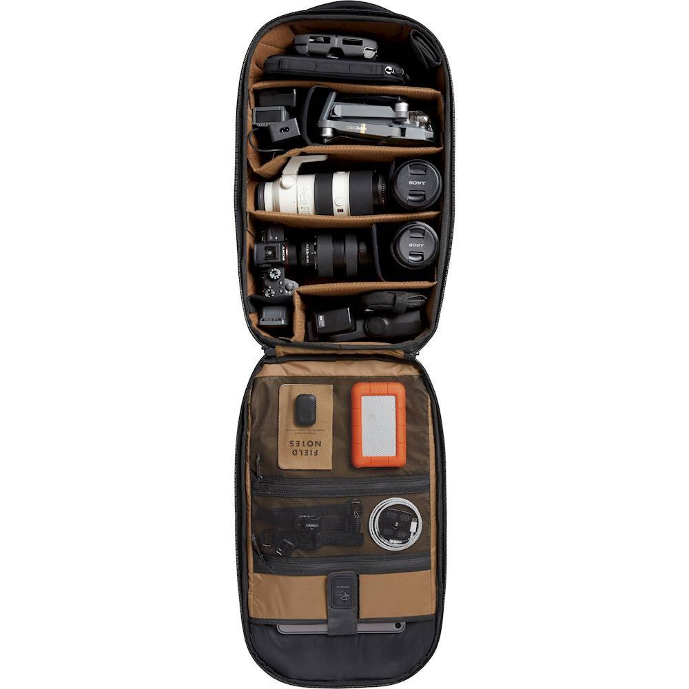 The image features a camera bag with various items inside, including a camera and a lens. The bag is open, revealing the contents, and it is placed on a white background. The camera bag is designed to hold a camera, lens, and other accessories, making it a convenient and organized way to transport photography equipment.