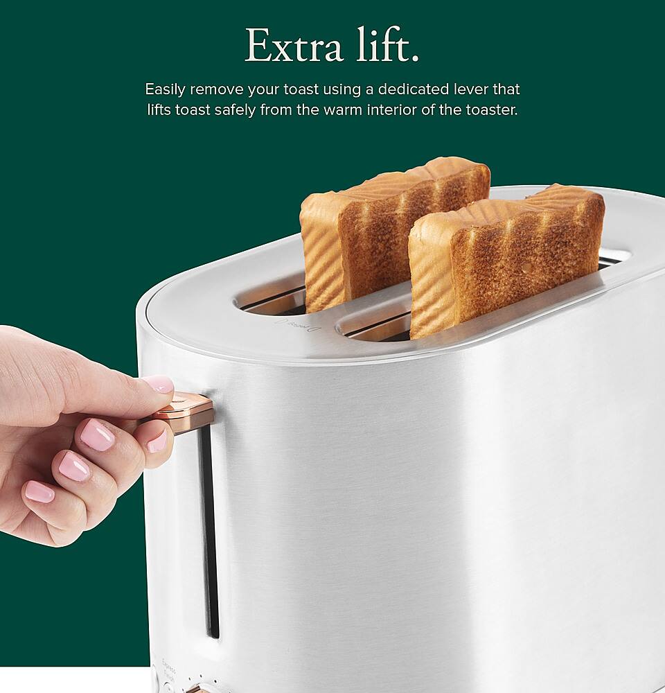 The image features a toaster with a dedicated lever that allows for easy removal of toast from the warm interior. The toaster is filled with toast, and a hand is seen pulling out a piece of toast from it. The toaster is designed to provide extra lift for the toast, ensuring that it is safely removed from the toaster without burning or sticking. This feature makes it convenient for users to enjoy their toast without any hassle.