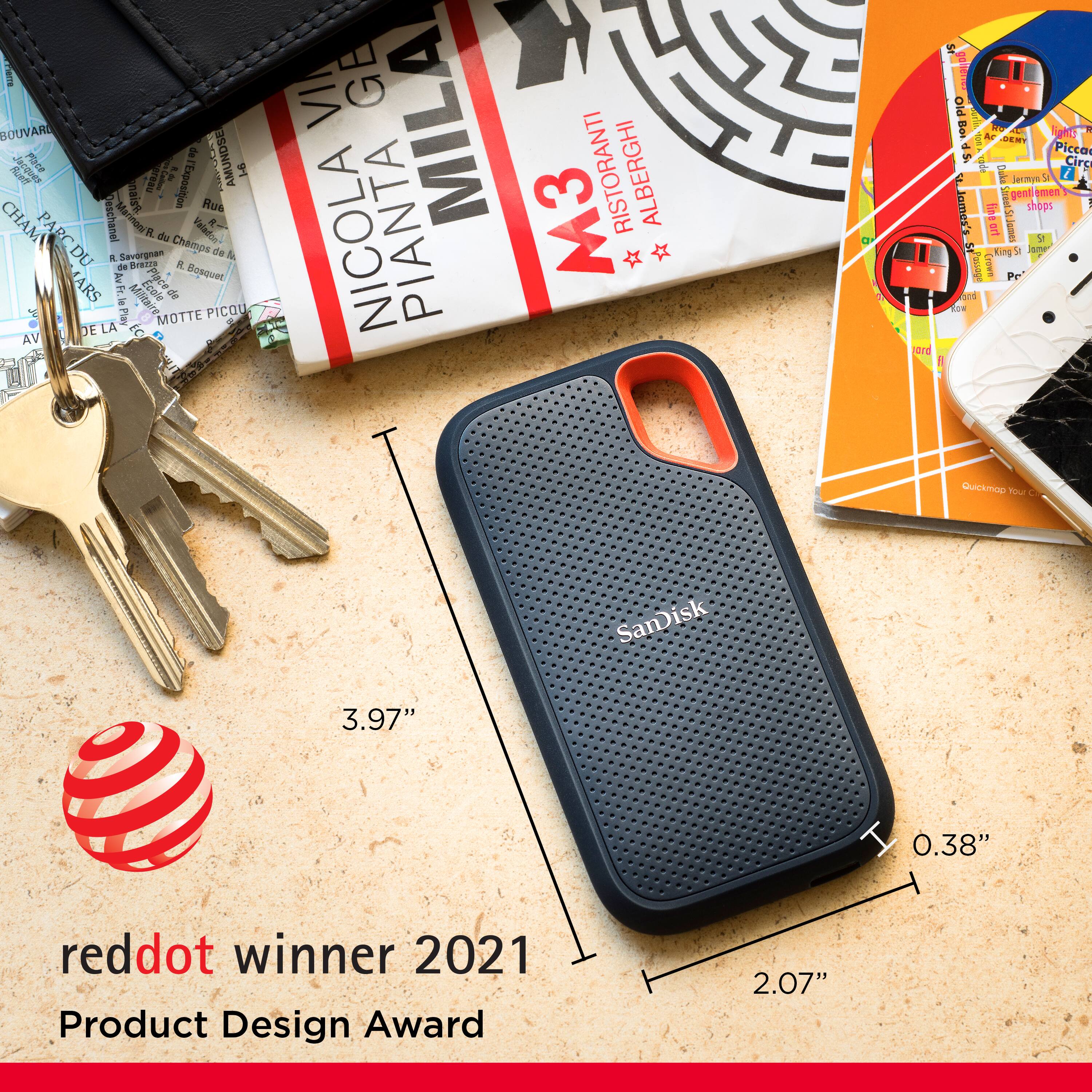 The image features a SanDisk phone case, which is a winner of the 2021 Product Design Award. The case is placed on a table next to a set of keys. There are also several books and a wallet nearby. The phone case is described as being 3.97 inches long and 0.38 inches wide, while the keys are 2.07 inches long.