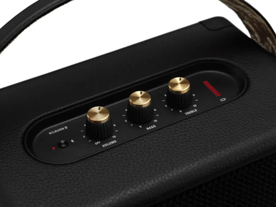 The text on the image reads "Kilburn * 8 - 2 - a - 2 8 - 10 OFF VOLUME I 0 8 - 10 BASS 4 - 2 I 8 - 10 0 TREBLE." This text is describing the features of a stereo system, with the "Kilburn" likely referring to the brand or model of the device. The text lists various settings for the volume, bass, and treble, indicating that the user can adjust these settings to customize the sound quality according to their preferences.