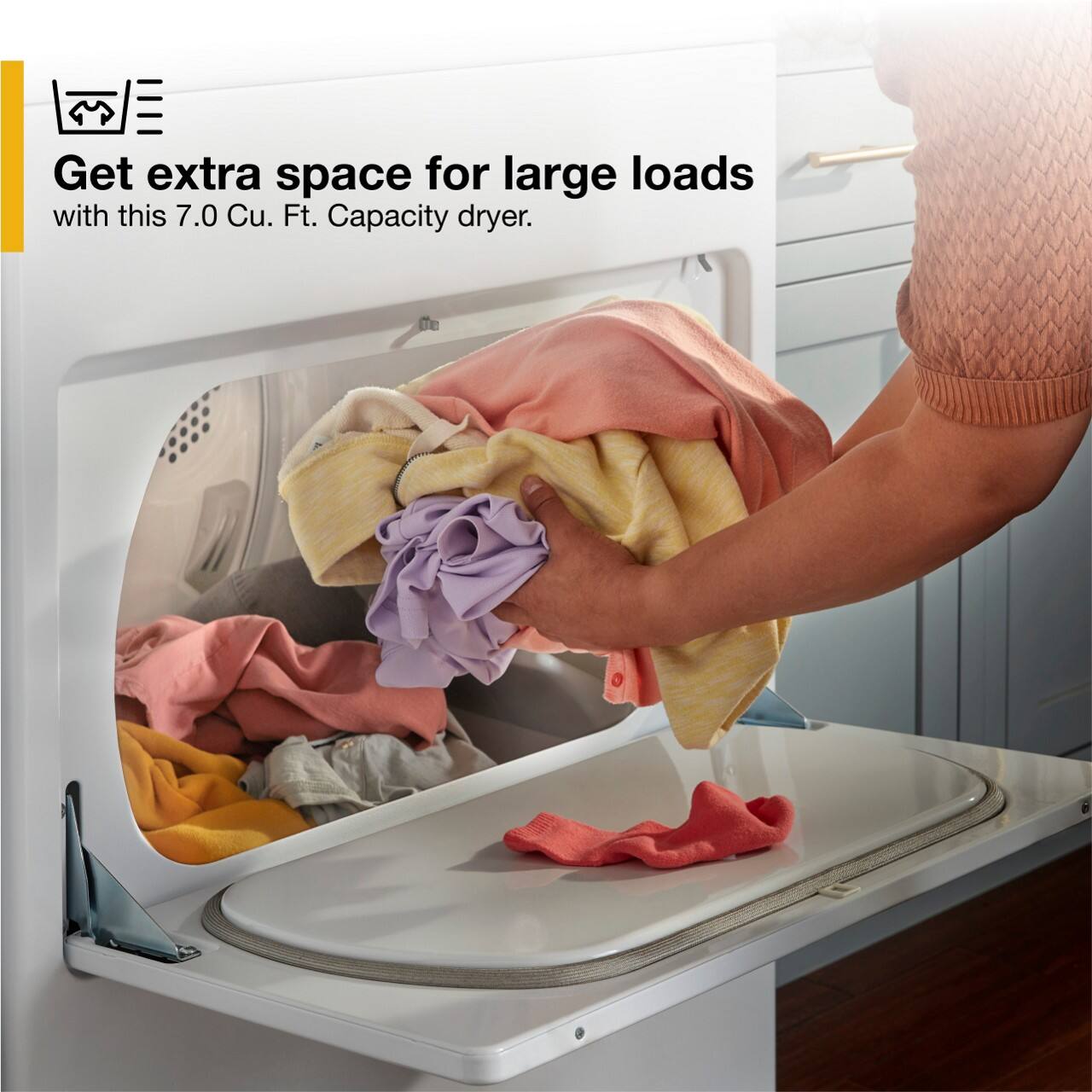 The image shows a person loading a washing machine with a large amount of laundry. The machine is filled with clothes, indicating that it has a large capacity. The person is putting clothes into the dryer, which also has a large capacity. The advertisement suggests that this dryer is ideal for handling large loads of laundry, providing extra space for drying clothes.