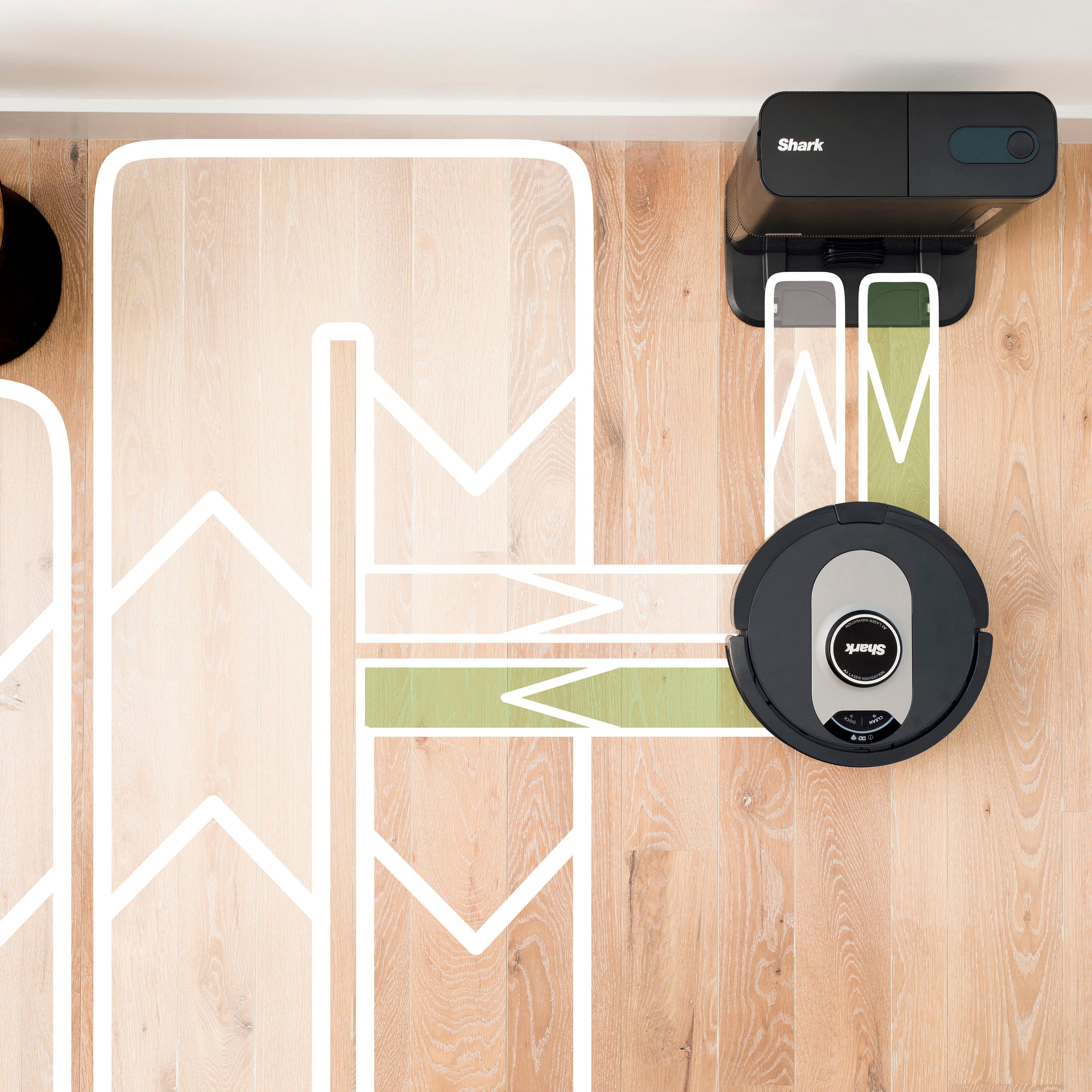 The image features a person holding a smartphone with a SharkClean app displayed on the screen. The app is designed to help users schedule whole-home cleanings or target specific rooms and spots to clean. The app is easy to use and can be accessed through the convenient app on the smartphone. The person is likely using the app to manage their cleaning schedule and ensure their home remains clean and well-maintained.