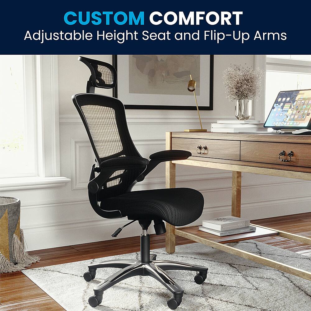 The image showcases a black office chair with adjustable height and flip-up arms, which is part of the Custom Comfort series. The chair is placed on a wooden desk, and there is a laptop nearby. The room also features a window, providing natural light to the space.
