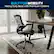 The image showcases a black office chair with a heavy duty base and premium casters, which is built for mobility. The chair is placed on a rug, and there is a desk with a laptop and a potted plant nearby. The scene suggests a comfortable and functional workspace.