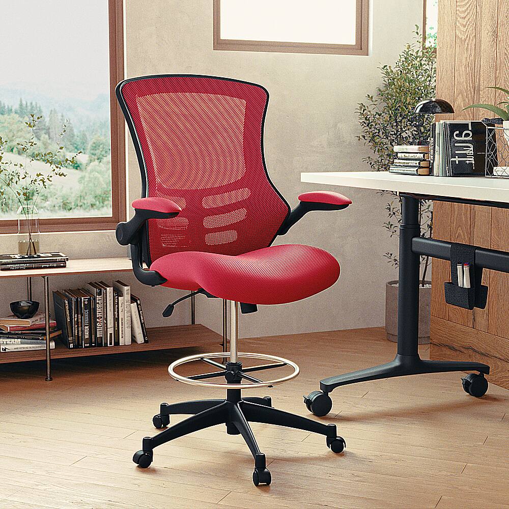 The image features a red office chair with wheels, placed in front of a desk. The desk is accompanied by a bookshelf filled with various books. There is also a potted plant nearby, adding a touch of greenery to the space. The scene appears to be a well-organized and comfortable workspace.