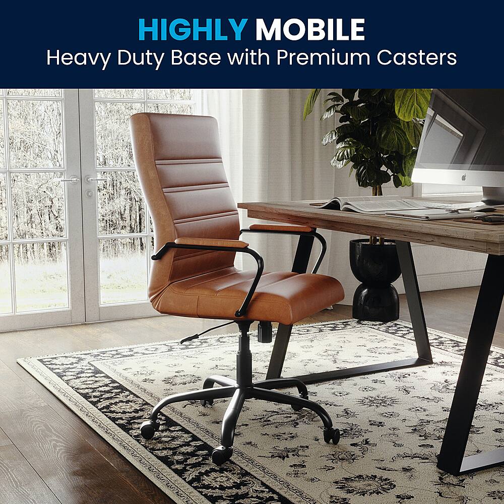 The image features a brown leather office chair with a heavy duty base and premium casters. The chair is placed on a rug in front of a desk, which has a laptop, a keyboard, and a mouse on it. The desk also has a potted plant and a TV nearby. The scene suggests a comfortable and functional workspace.