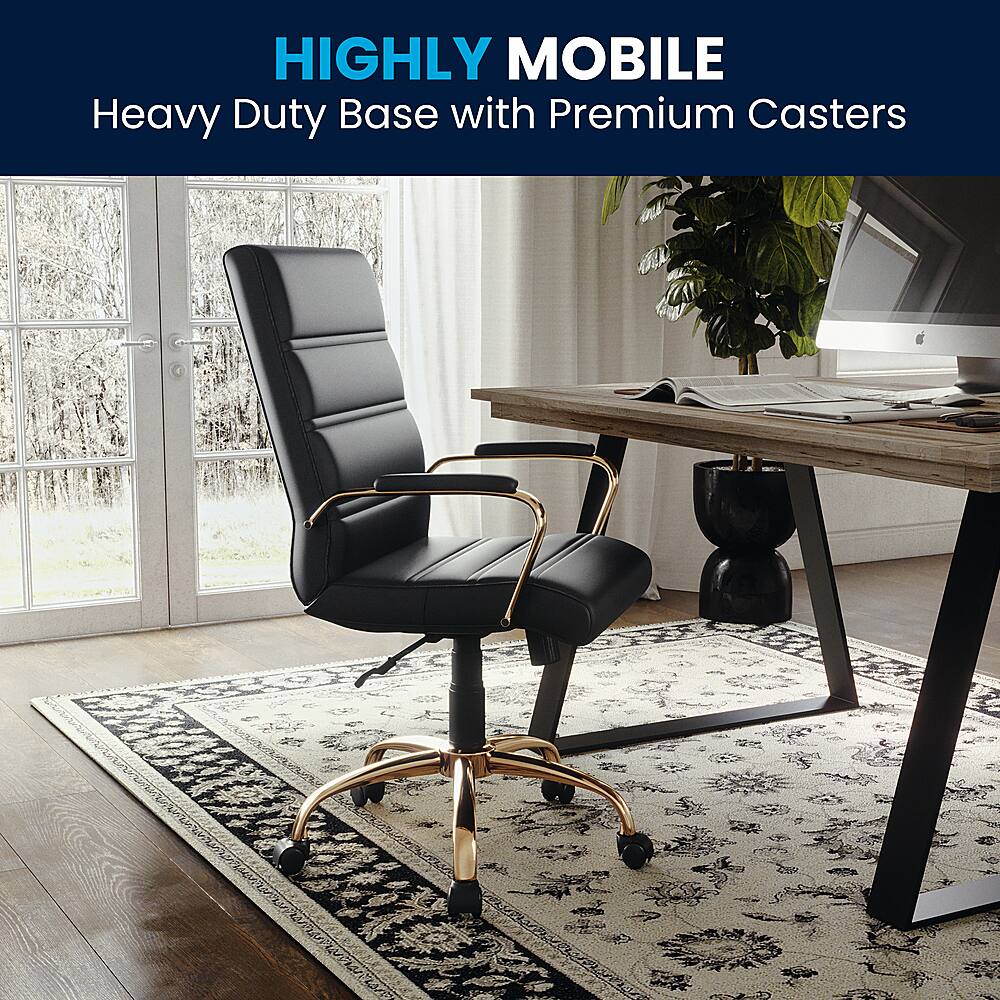 The image features a black office chair with a heavy duty base and premium casters, which provide added stability and mobility. The chair is positioned on a rug, and there is a desk nearby with a laptop and a keyboard on it. The scene also includes a potted plant and a TV, creating a comfortable and functional workspace.